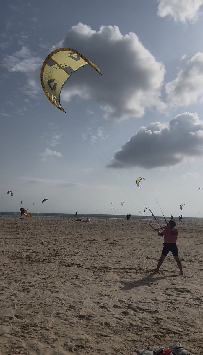 Taras en la playa con la cometa de kitesurf en el aire