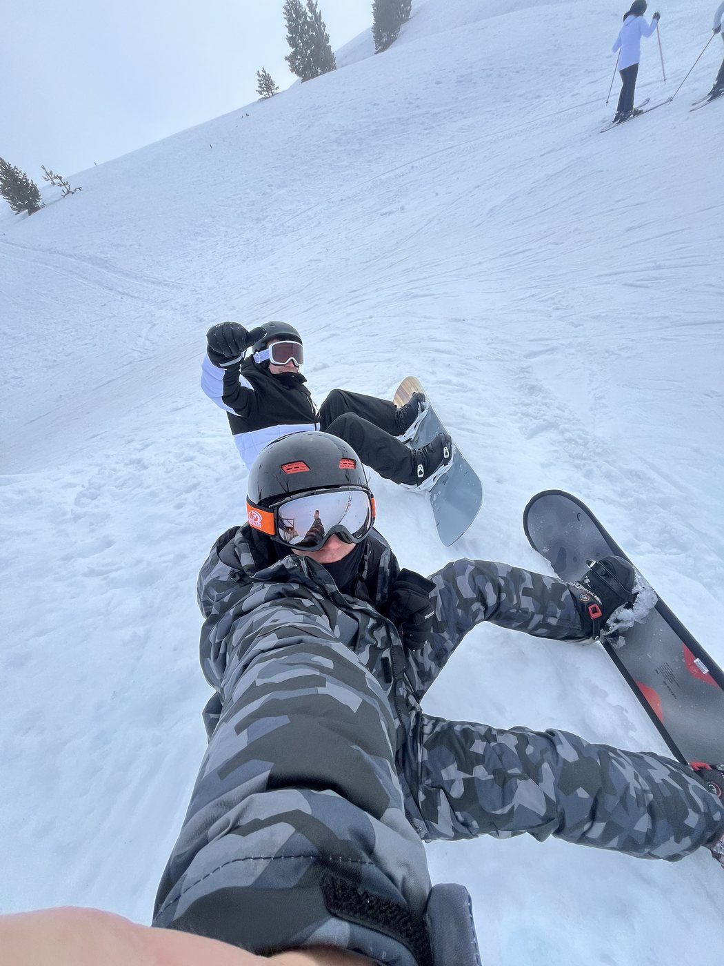 Taras sentado en la nieve con la tabla de snowboard y un amigo al lado