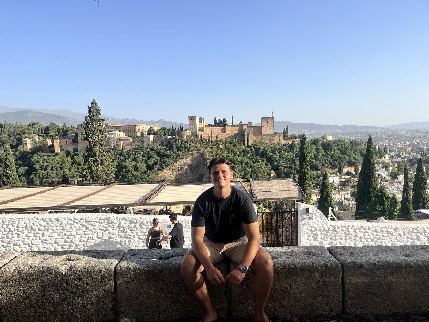 Taras sentado en un mirador con la Alhambra al fondo