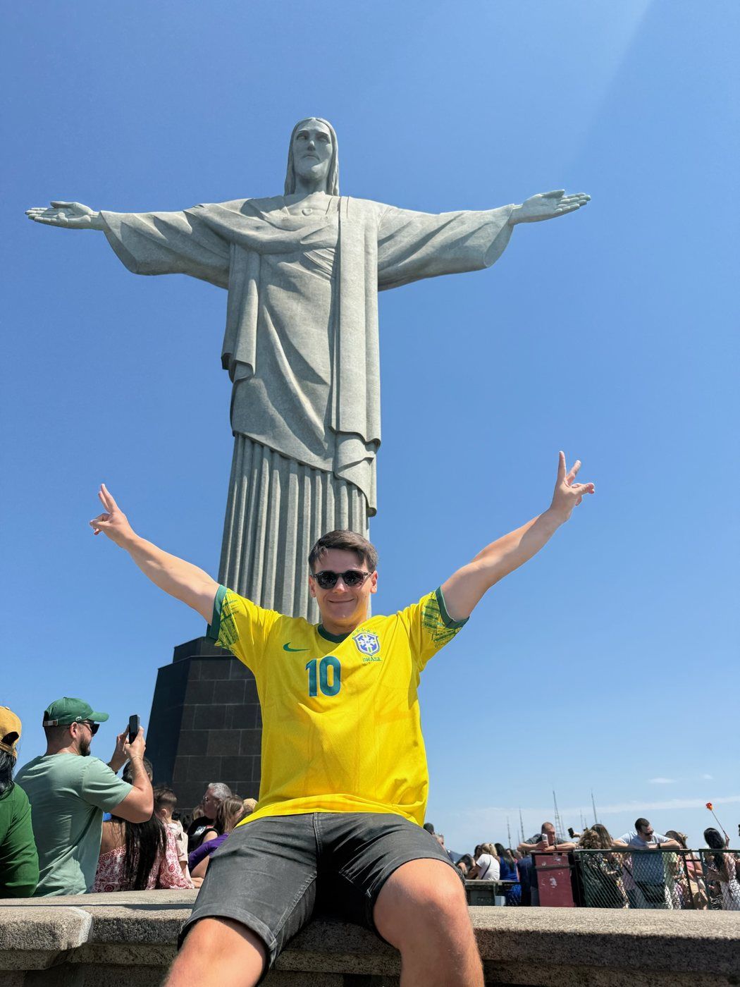 Taras con la camiseta de Brasil y los brazos abiertos delante del Cristo Redentor